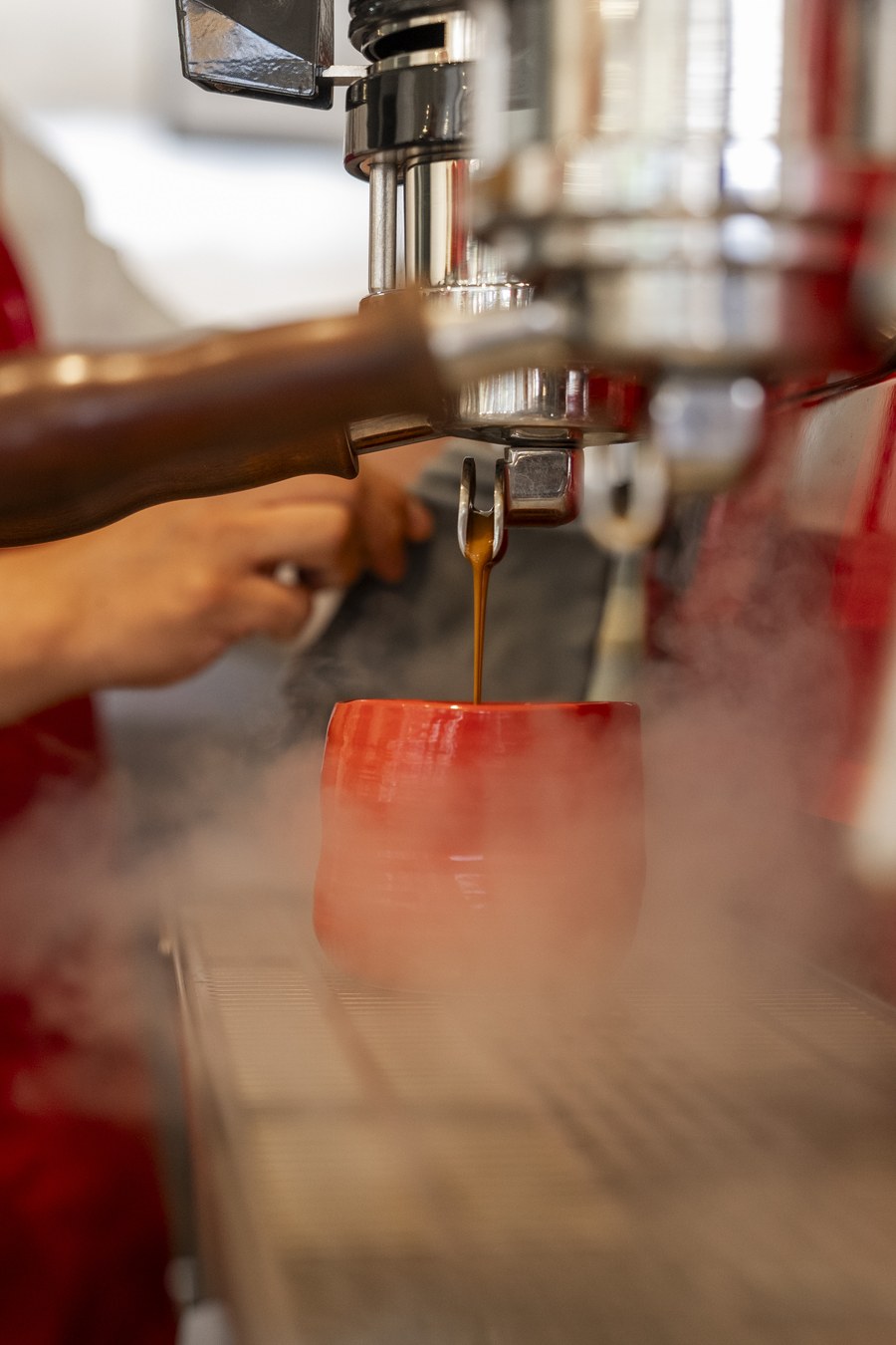 Espresso cayendo en una taza roja en la máquina de la barra